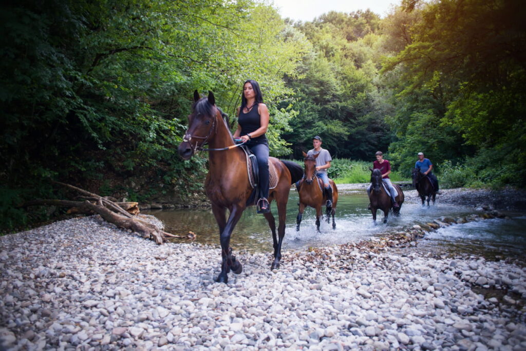 A group of friends riding a horse while crossing a river