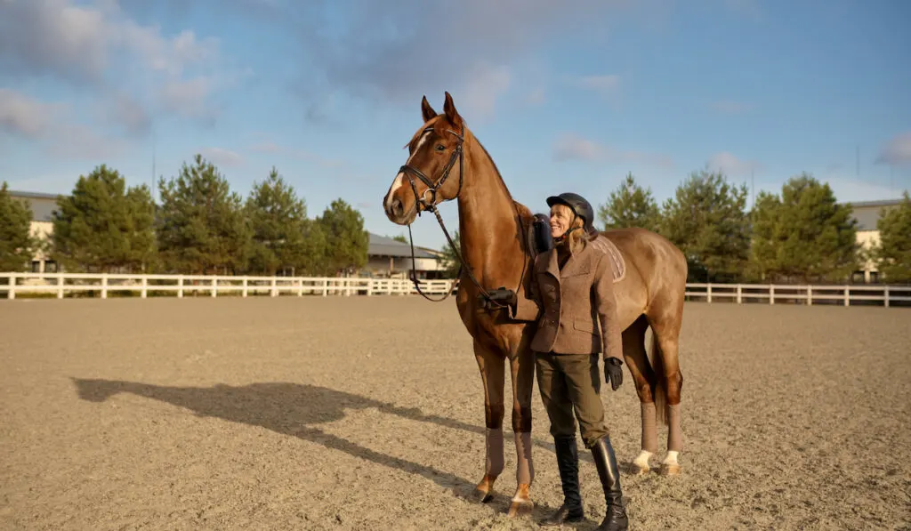 A horse trainer with her stallion outdoors in farm
