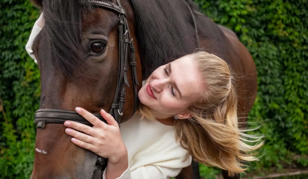 Beautiful woman hugs a horse muzzle 