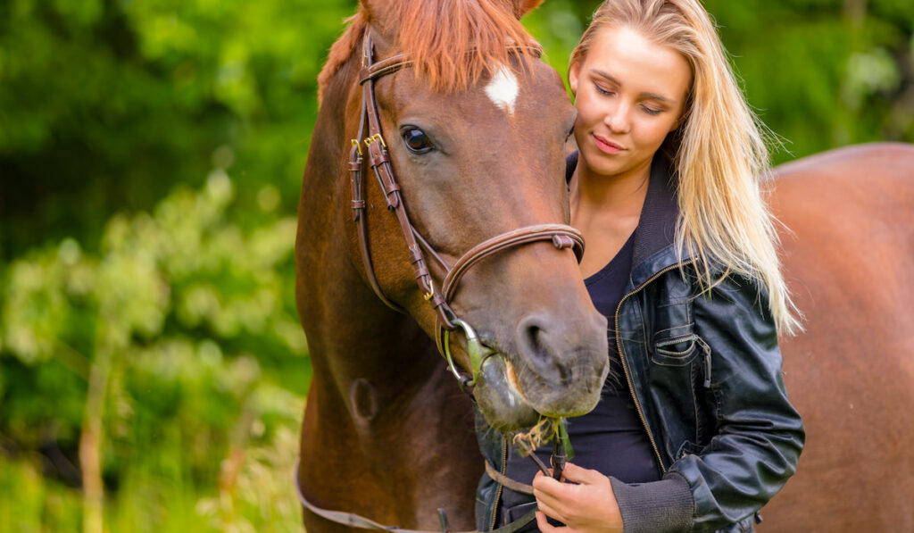 Beautiful young woman with her arabian horse in the field
