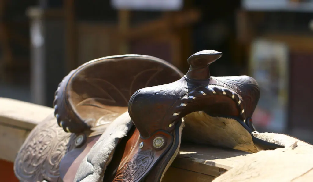 Brown western style saddle on the wooden fence