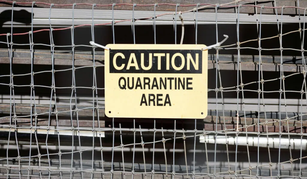 Caution Quarantine Area sign on metal fence