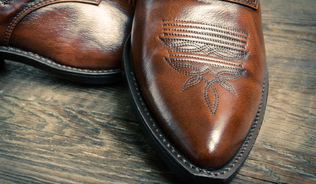 leather cowboy shoes on wooden table 