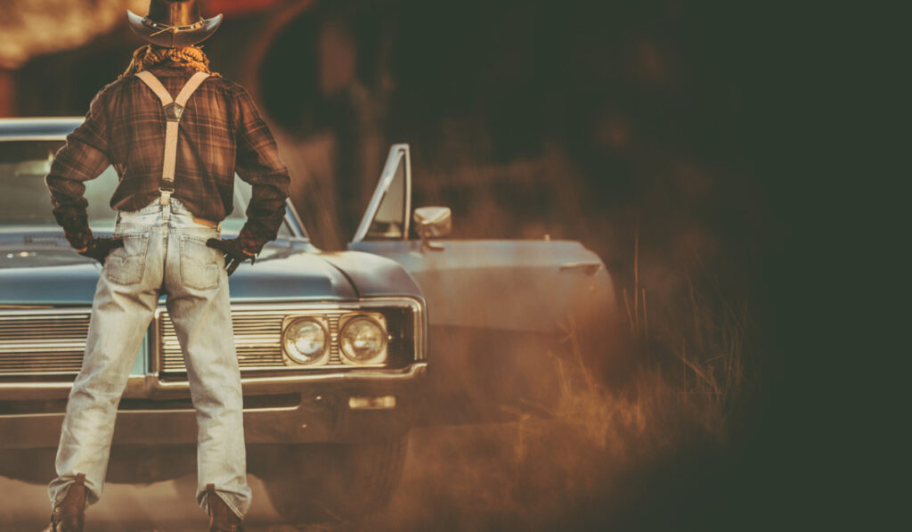 cowboy standing in front of his blue car