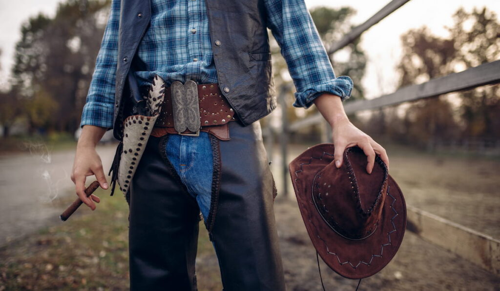 Cowboy in leather clothes poses with cigare 