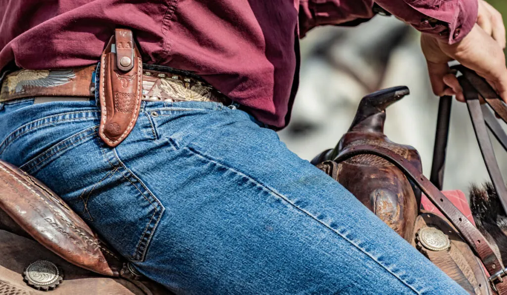 Cowboy riding his horse with pocket knife and wearing blue jeans
