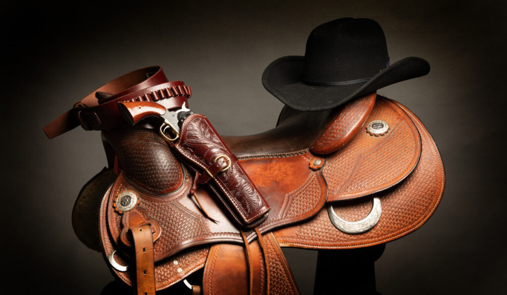 Cowboy saddle, stetson hat and remington revolver