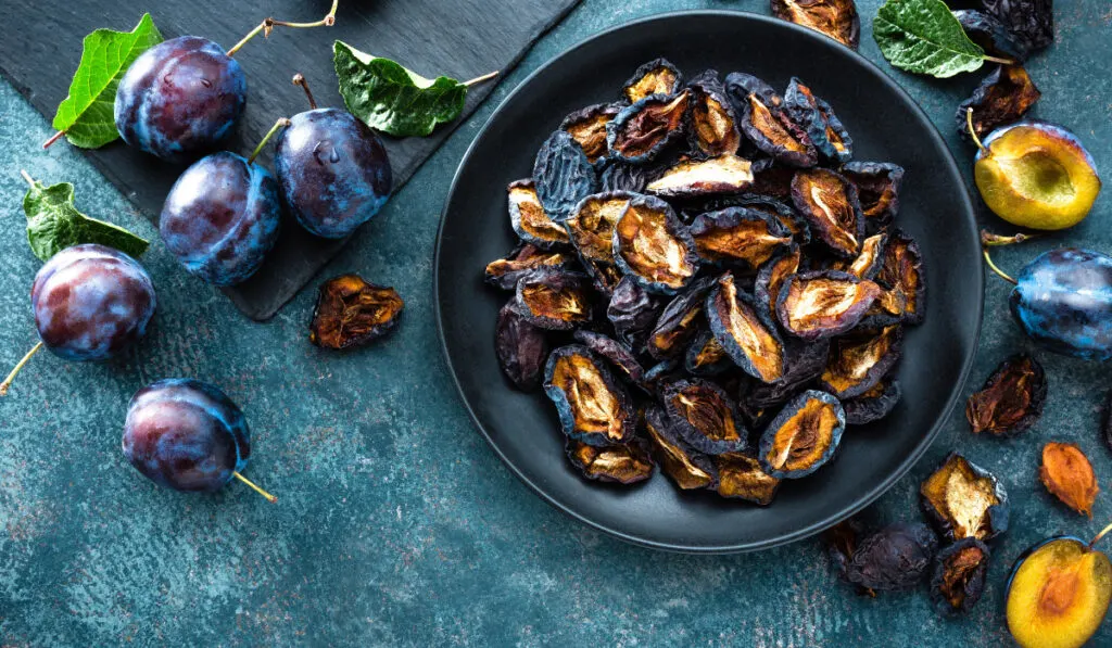 Dried prune and fresh plums with leaves
