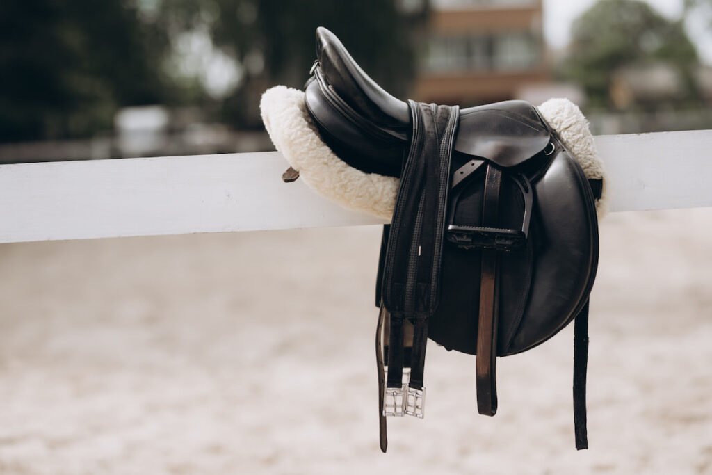 English saddle hanging on a wooden stable door
