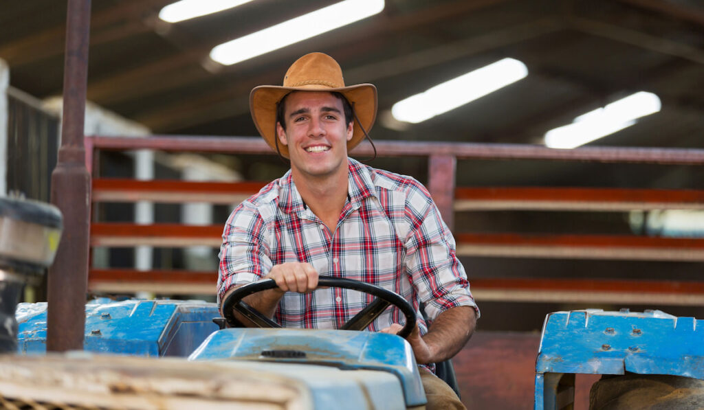 Happy young cowboy driving a tractor