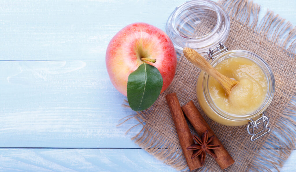 Homemade apple pure in a jar and whole apple on the table