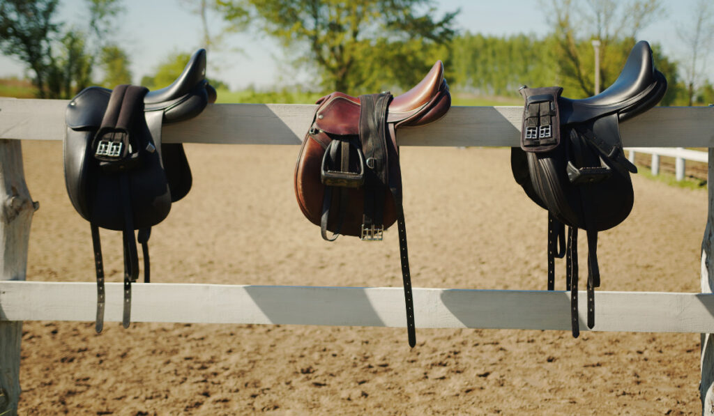 Leather saddles hanging on the wooden fence