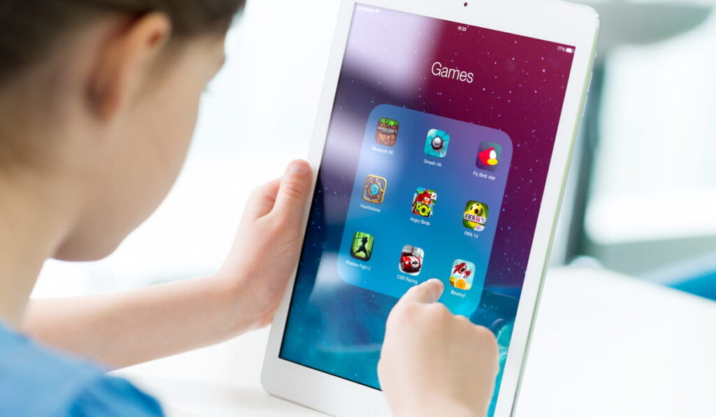 Little girl looking on a brand new Apple iPad Air with various game applications on a screen. 