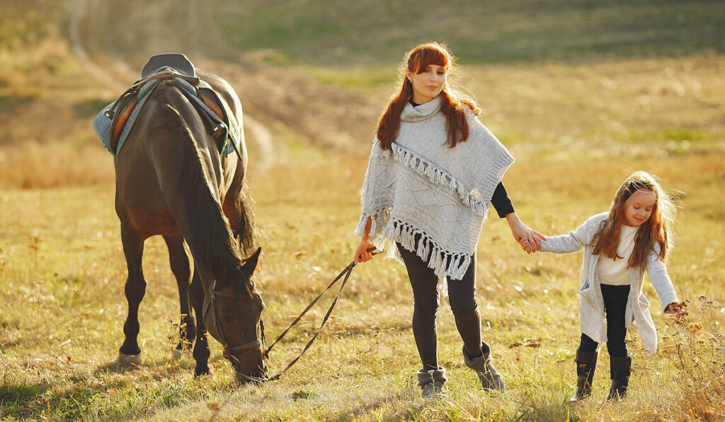 Mother and daughter in a field playing with a horse 