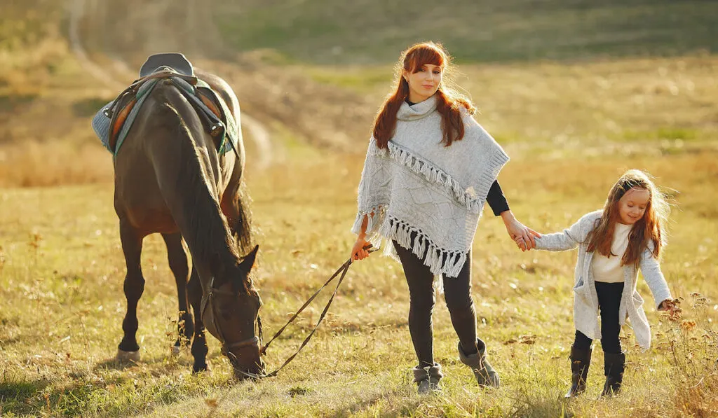 Mother and daughter in a field playing with a horse