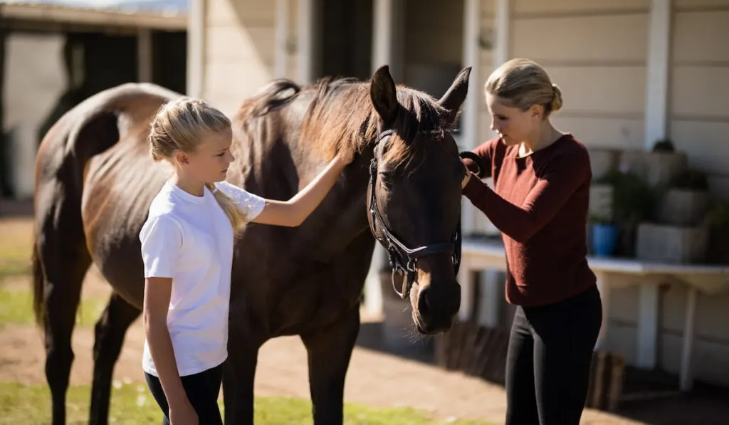 Mother and daughter touching the horse 