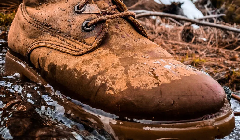 One wet cowboy boot stepping on the water in the mountains
