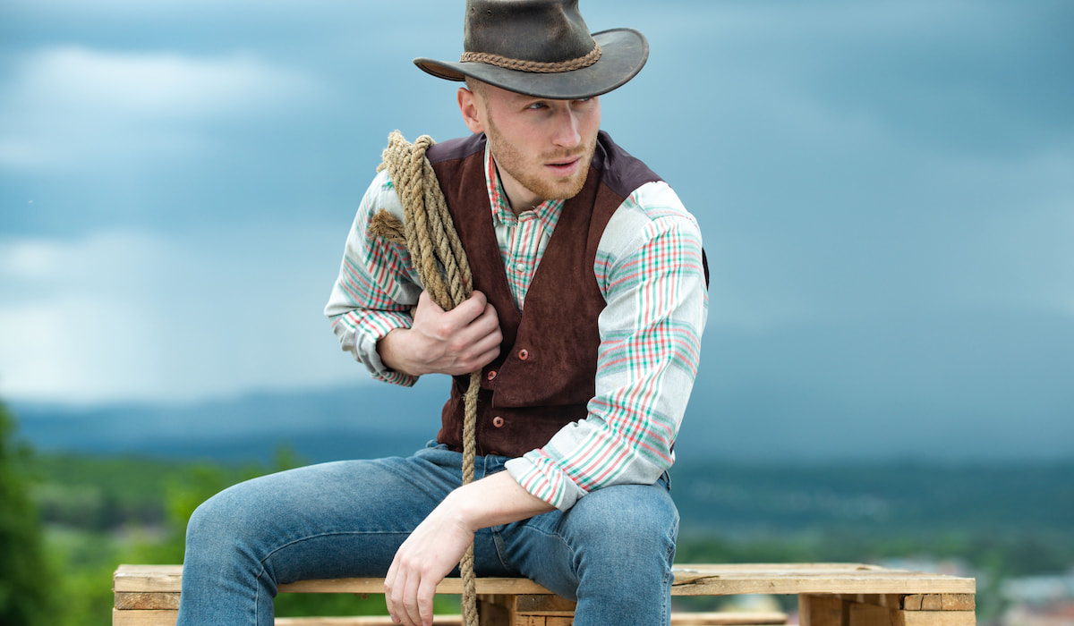 https://www.helpfulhorsehints.com/wp-content/uploads/Portrait-of-a-cowboy-sitting-outdoor-holding-his-lasso-rope-and-wearing-vest-ss221214.jpg