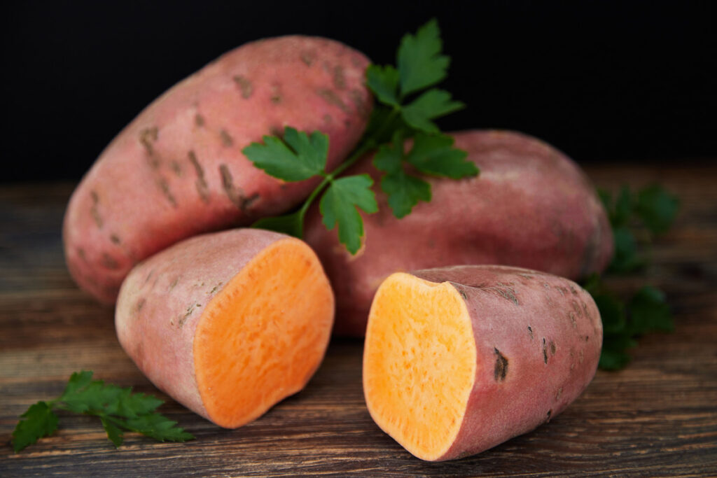 Tree sweet potatoes (batatas), one of which is cut into two halves, on the rustic wooden table