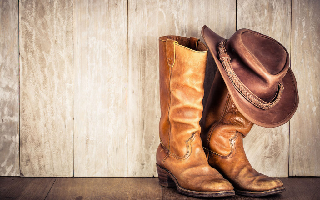 Wild west retro leather cowboy hat and rounded old boots, vintage style on wooden background