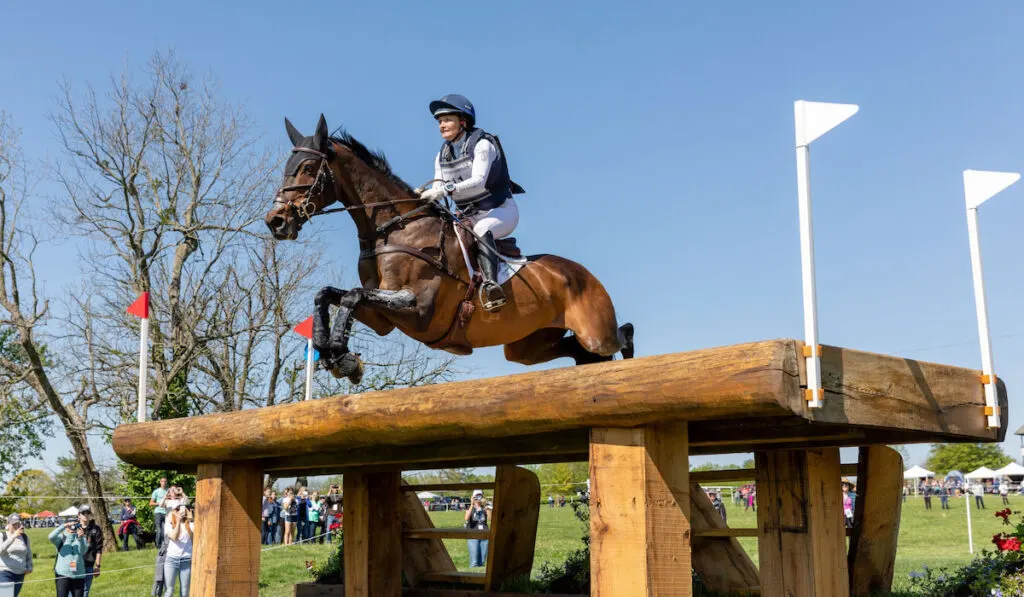Woman and her horse jumping over an obstacle in an horse eventing