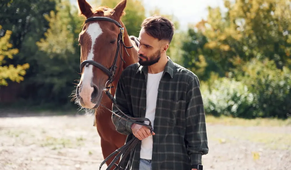 Young man with a horse holding the rein