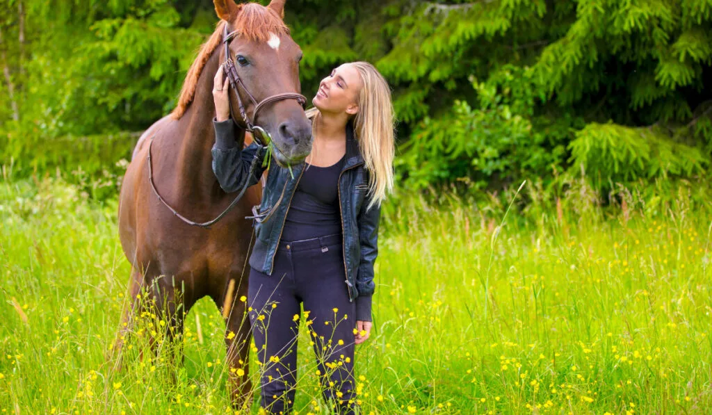 Young woman with her arabian horse standing in the field ee220326