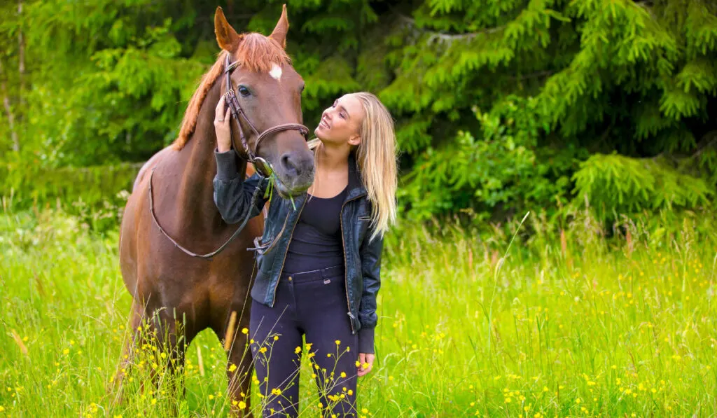 Young woman with her arabian horse standing in the field