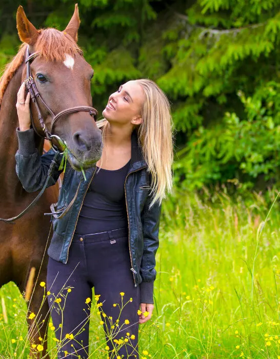 Young woman with her arabian horse standing in the field