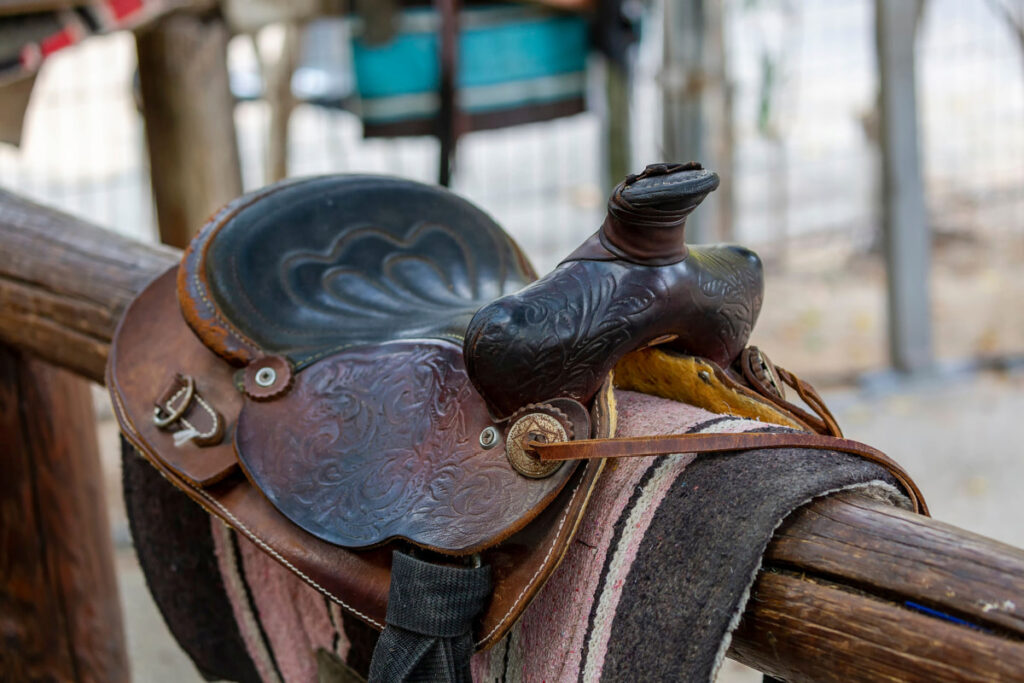 a brown horse saddle on top of a wooden fence