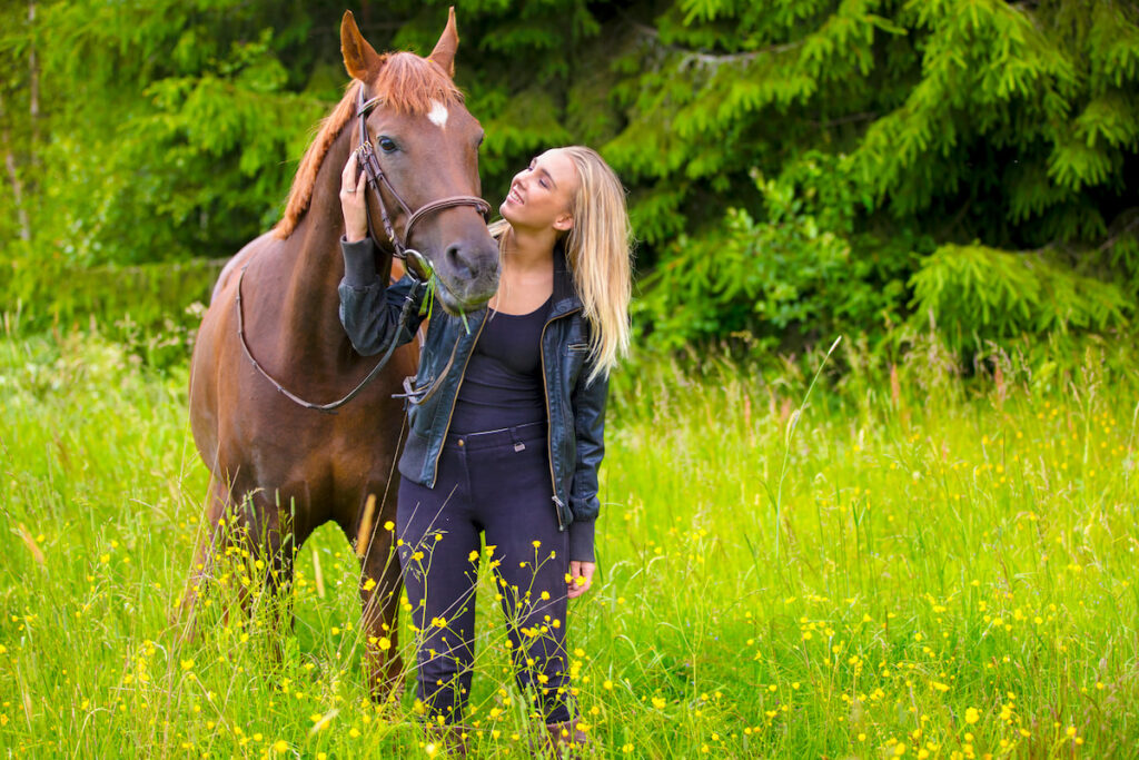 a girl standing with an Arabians horse in a green field