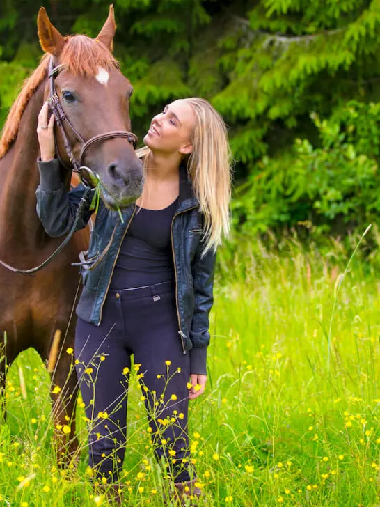 girl standing with an arabian horse in a green field