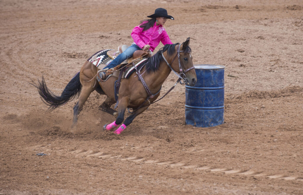 cow girl in pink riding on a saddle during barrel racing
