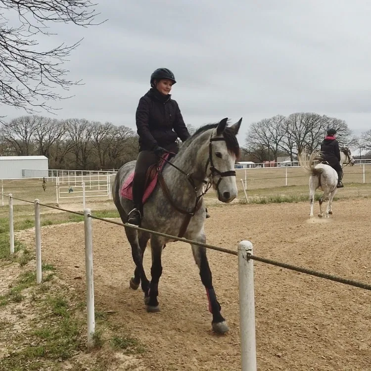 Young woman riding her gray mustang mare