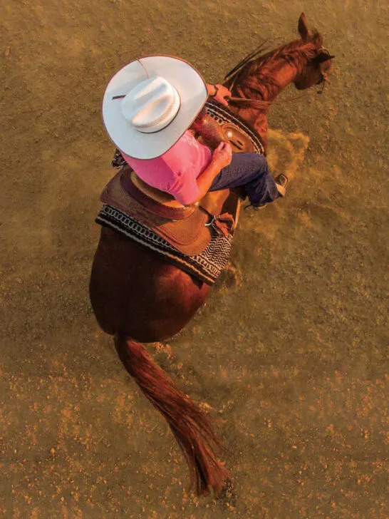 photo shoot seen from above of a cowboy woman riding her horse doing a spin - ss230708