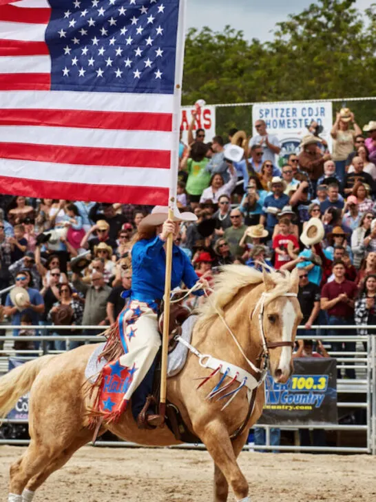 woman holding an american flag during a ceremony before a rodeo event