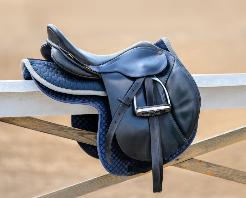 english jumping saddle hanging on a white fence