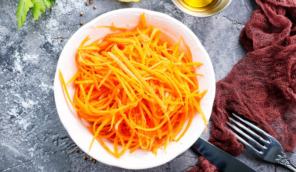 grated carrot in bowl and on a table