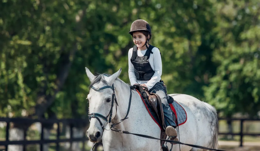 happy young girl riding a horse