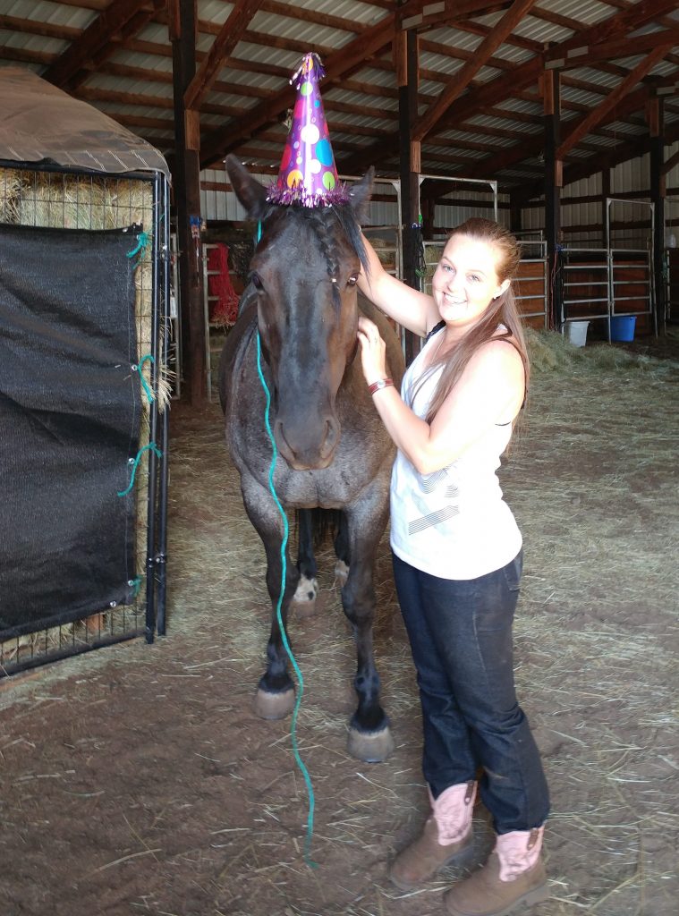 Young woman with her horse with birthday hat