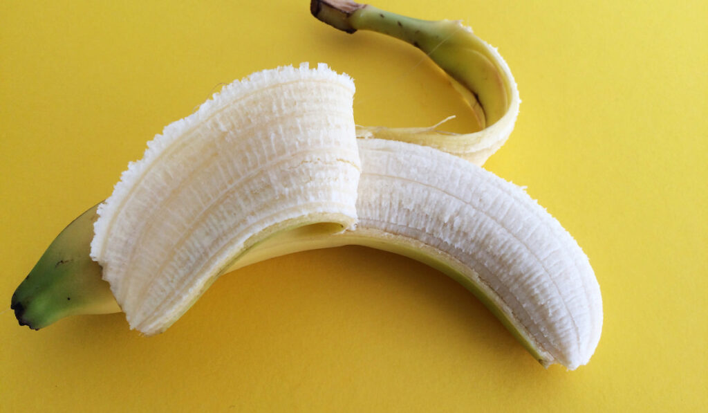 peeled banana on yellow background 