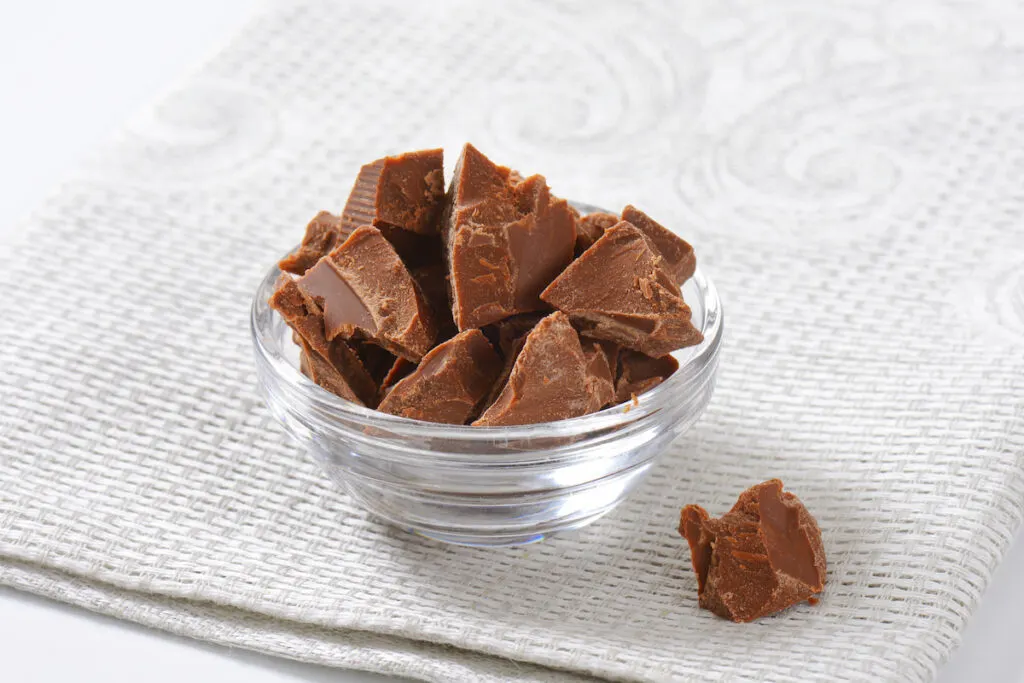 pieces of milk chocolate in a transparent bowl on a table cloth