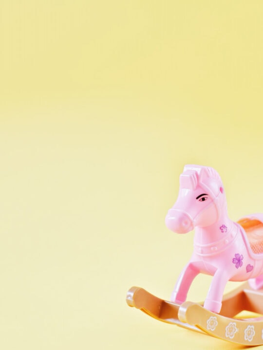 pink rocking horse toy on yellow background