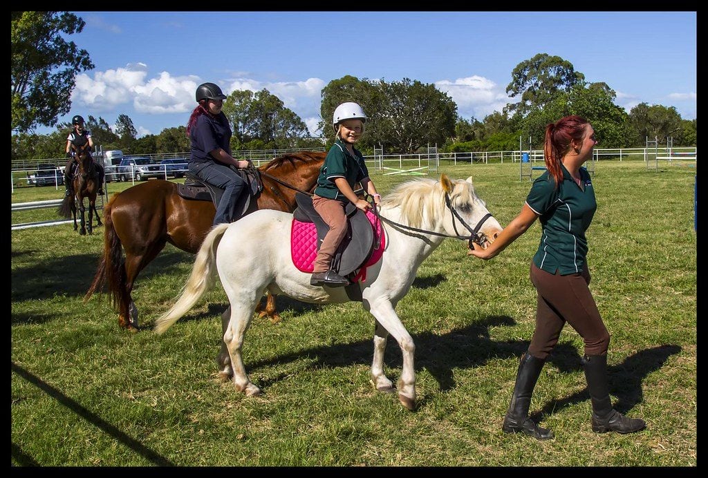 professional instructor guiding a kid riding a horse 