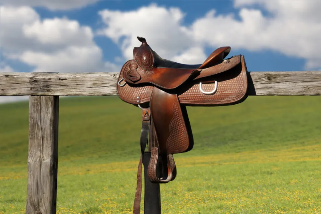 ranch saddle on top of a wooden fence under a nice clear weather
