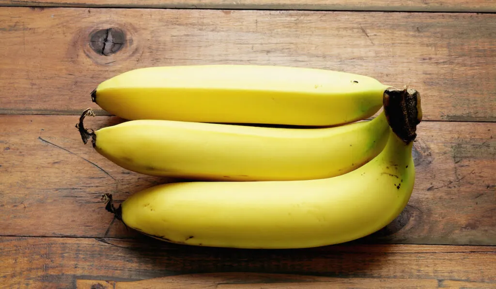 three bananas on a wooden table