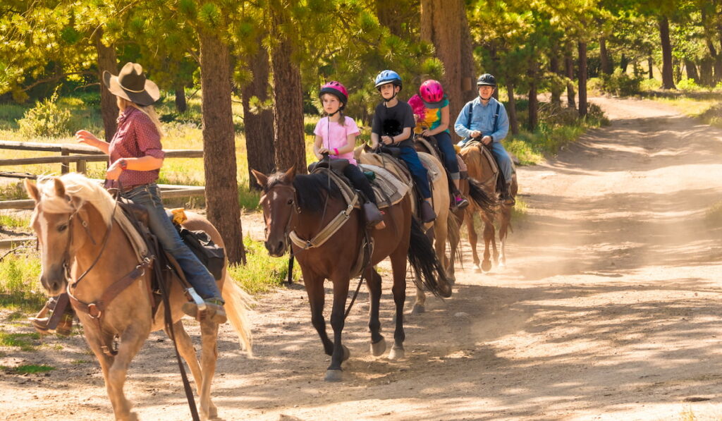 trainer helping young kids ride their horses