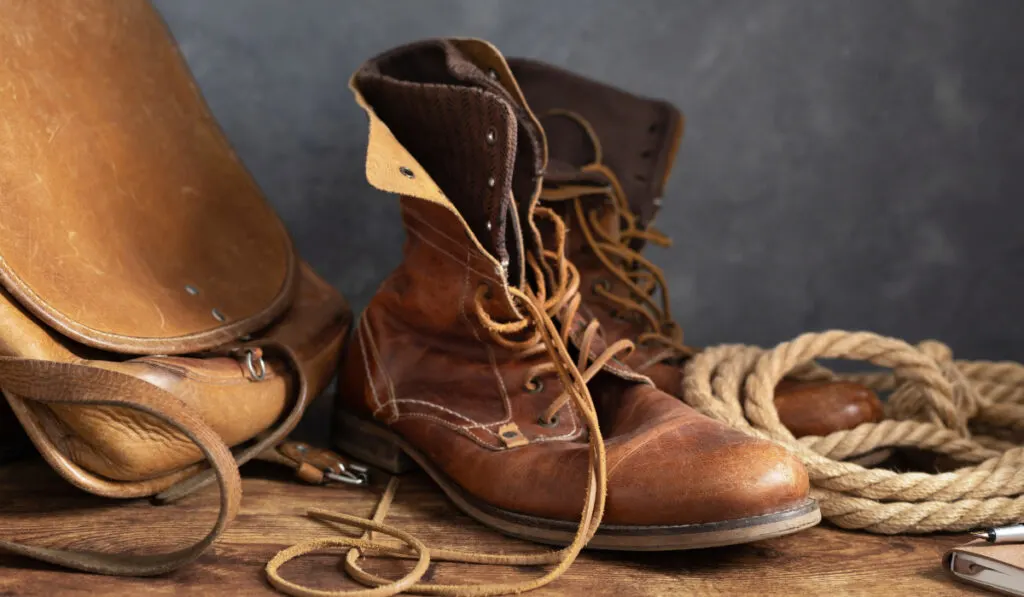 old leather travel vintage boots shoes and bag at table
